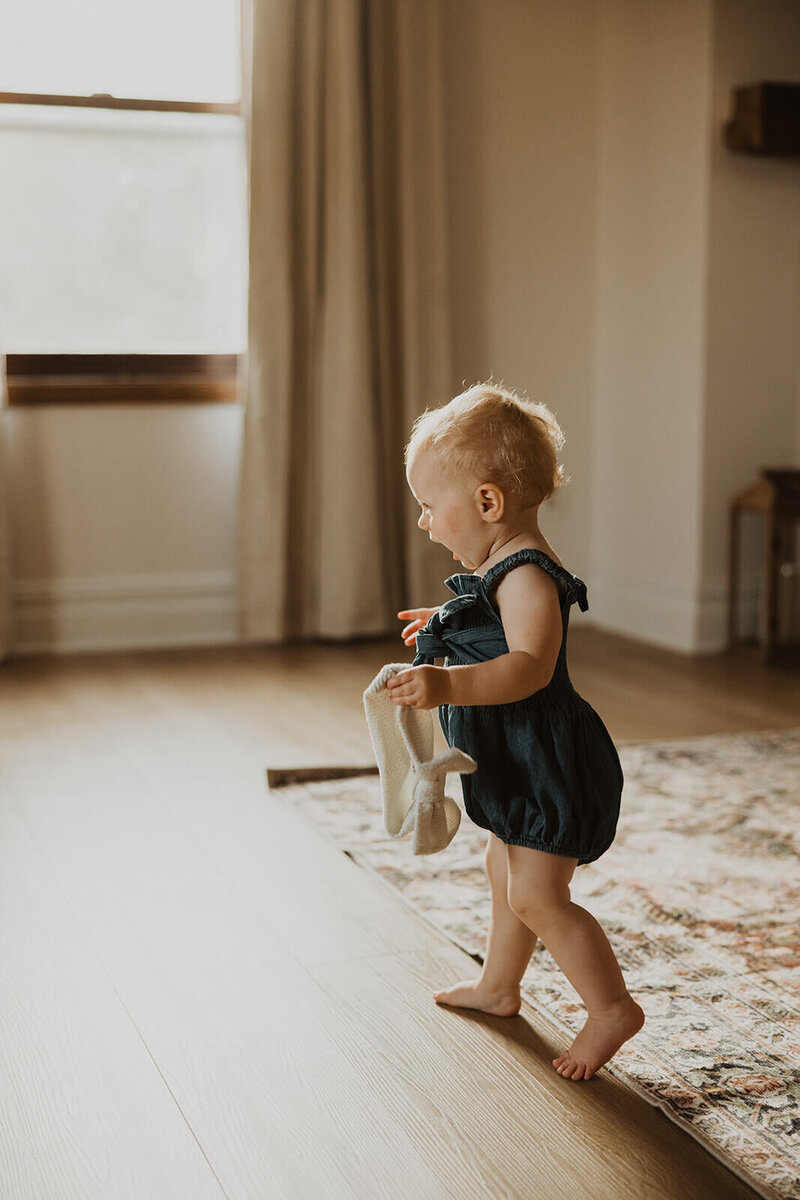 Toddler takes tentative steps across hardwood floor of living room