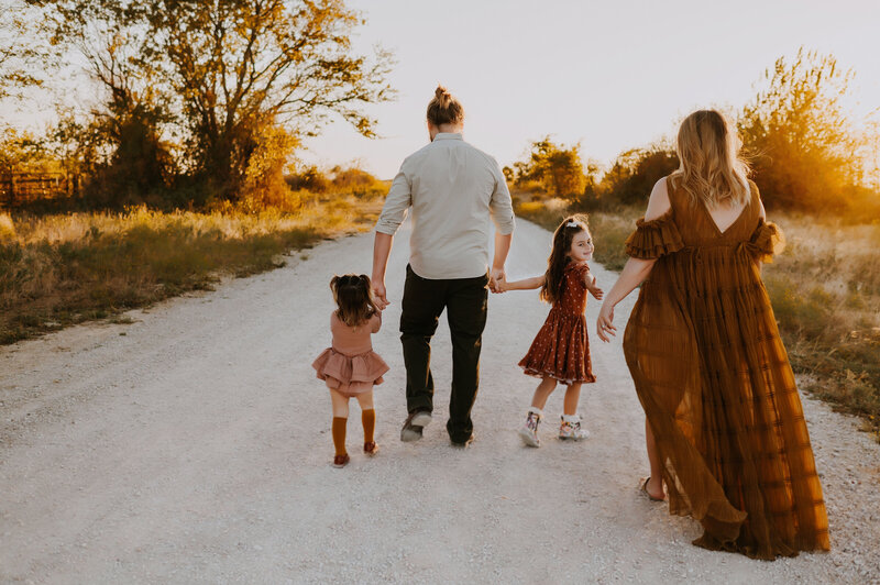 A family of four walking towards the sunset in coordinating outfits.