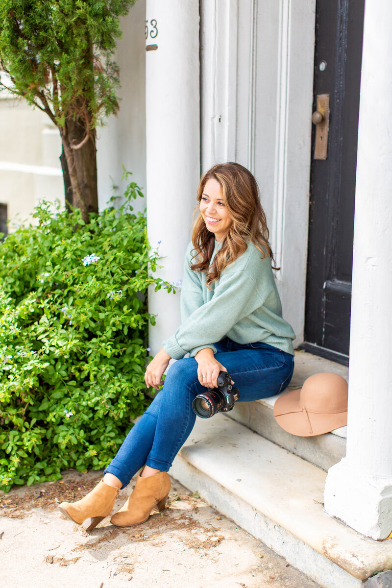 Woman holding a camera sits on front steps