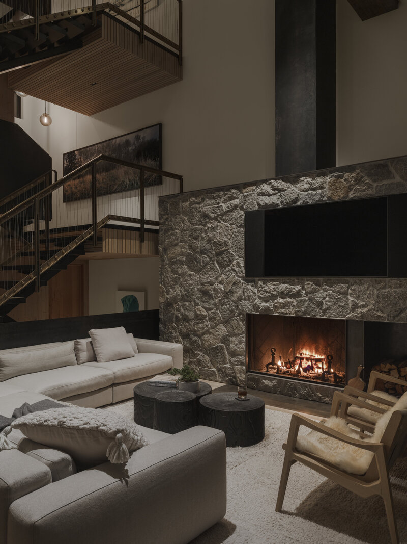 Modern living room area at Whistler cabin with natural stone fireplace designed by Los Angeles architect.