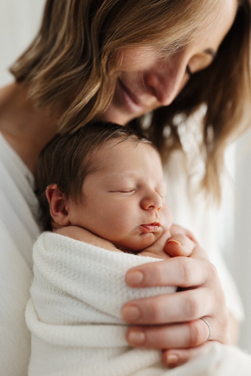 A mother holding her newborn baby while photographed by Christchurch photographer Lucy Jane Photography