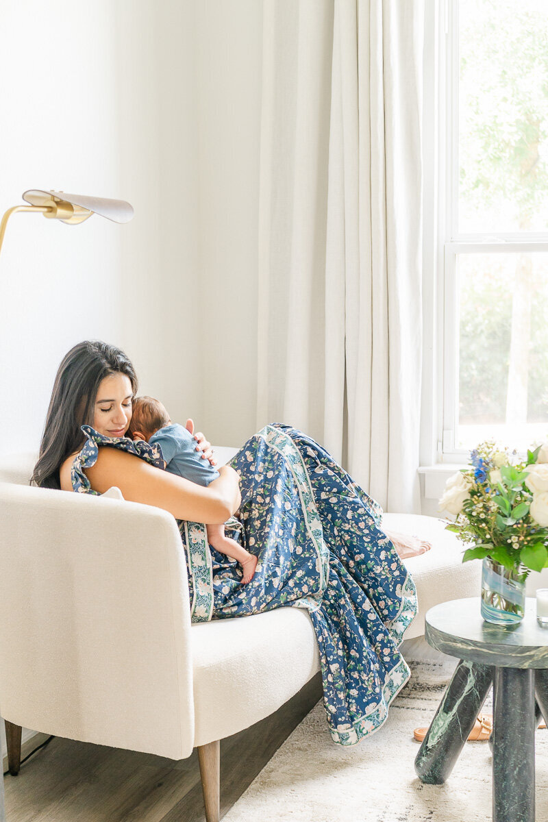 a mother with her infant child sit on a day bed in the sitting room of an Austin home.