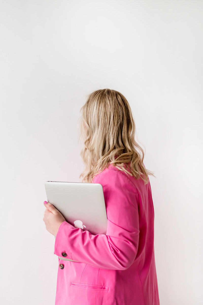 Kat Murphy in a pink blazer holding a laptop