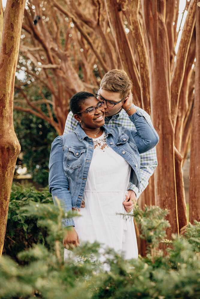 Guy embracing his fiancé and giving her a kiss on the cheek during their engagement session in Nashville, TN