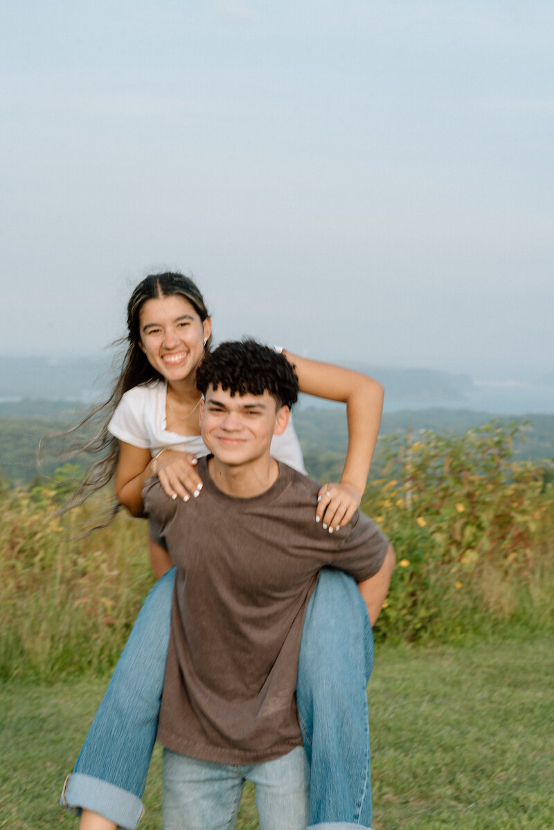 Couple sharing a playful piggyback ride at Sam Lewis State Park, capturing candid joyful moments in a natural outdoor setting.