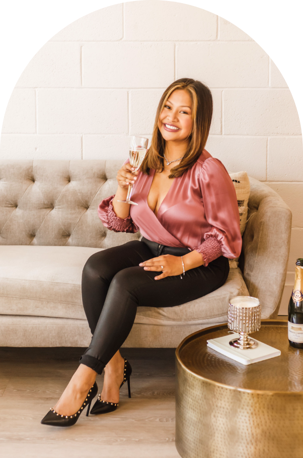 woman in pink sitting on a couch  holding wine glass