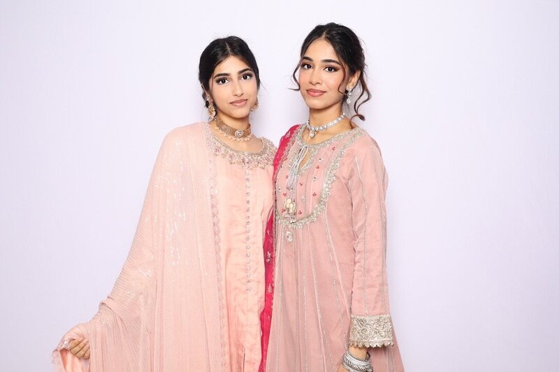 Two women in pastel peach embroidered dresses posing elegantly in front of a light backdrop at AR Photobooth.