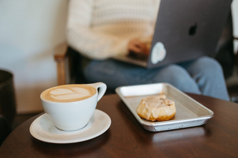 Two coffee cups filled with coffee on a white brick, centered around SEO FAQs for working with The Comma Mama Co.