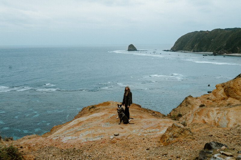 Dominique standing with pups cliffside overlooking the ocean