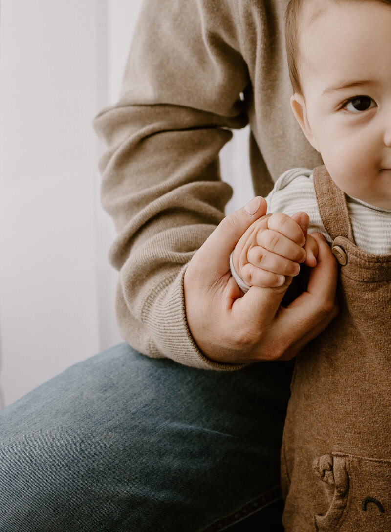 Toddler holding his father's hand.