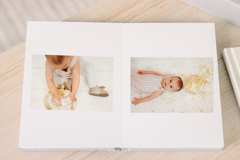 Album open on table displaying cake smash photos.
