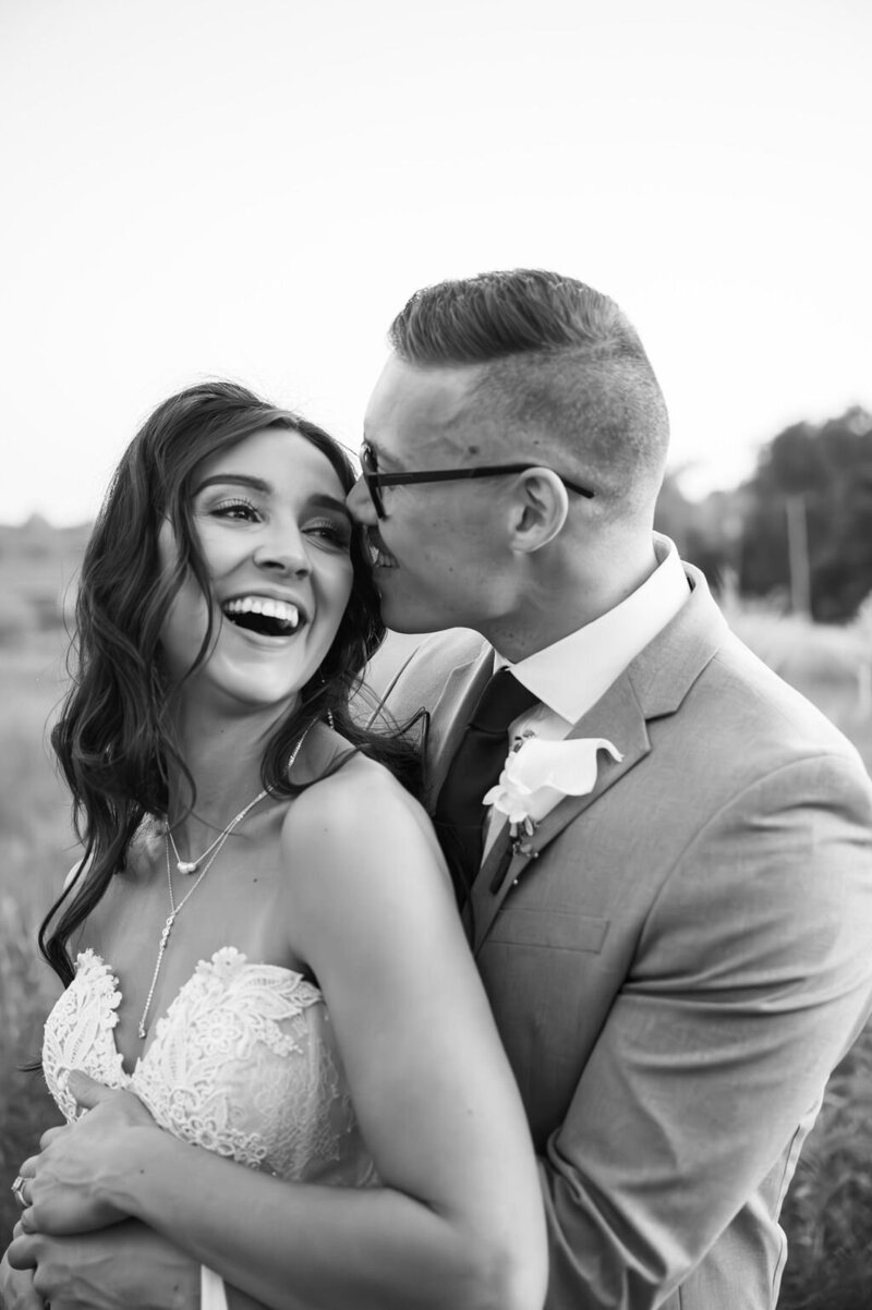 newly married couple in field next to barn wedding venue