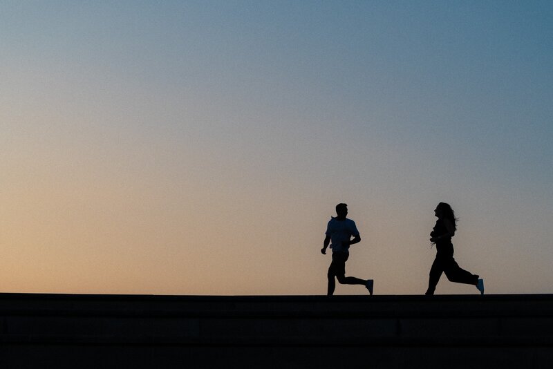 Silhouette of a couple running along the horizon at sunset at Coxhall Gardens in Carmel, Indiana