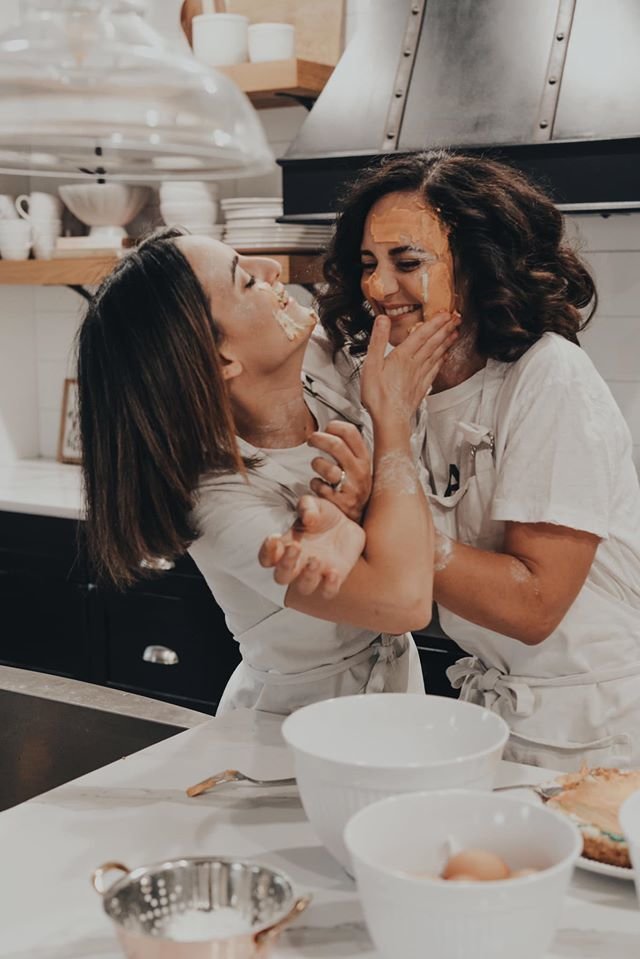 Owners and sisters of Layered Cake Artistry, Elena and Concetta, pictured laughing and putting buttercream  on eachother's faces