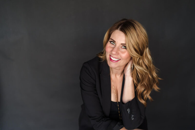 Modern headshot of female entrepreneur leaning on hand against black background in Kelowna photography studio