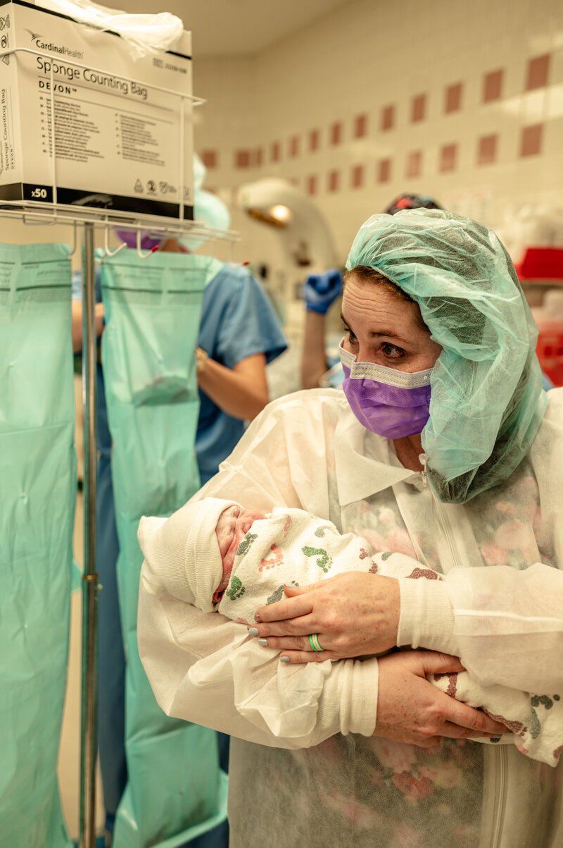 Mother meeting her baby for the first time during cesarean delivery — hospital birth photography in Aledo by Poppy + Blue Photography