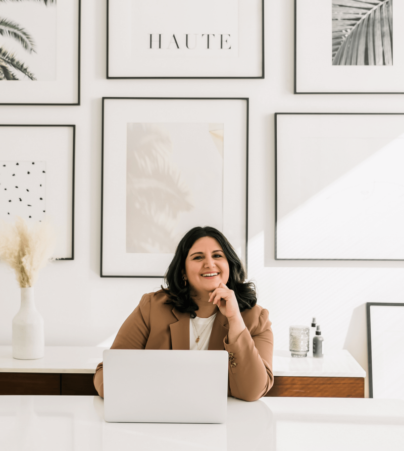 Rachel, the Founder of  Haute Stock Photo and stock video library for women entrepreneurs, sitting at her desk behind her laptop