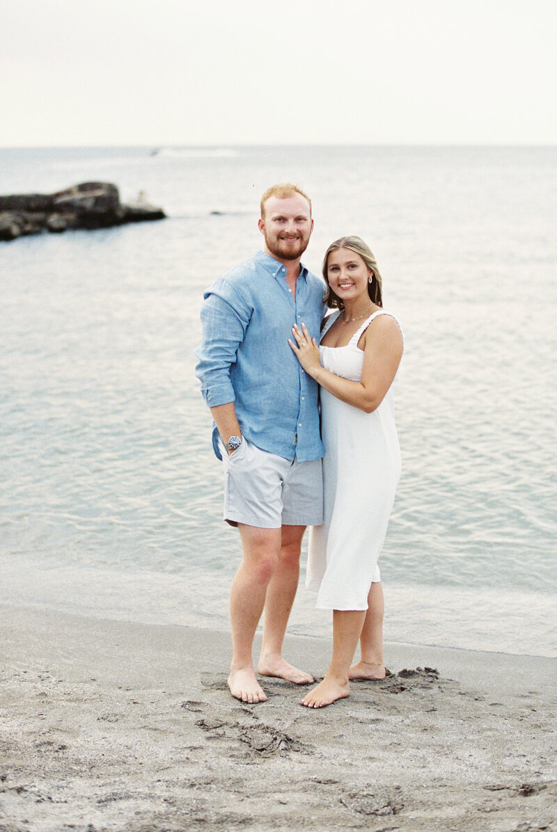 Engaged couple standing barefoot on the beach during a relaxed summer engagement session, captured by Cleveland Ohio engagement photographer.