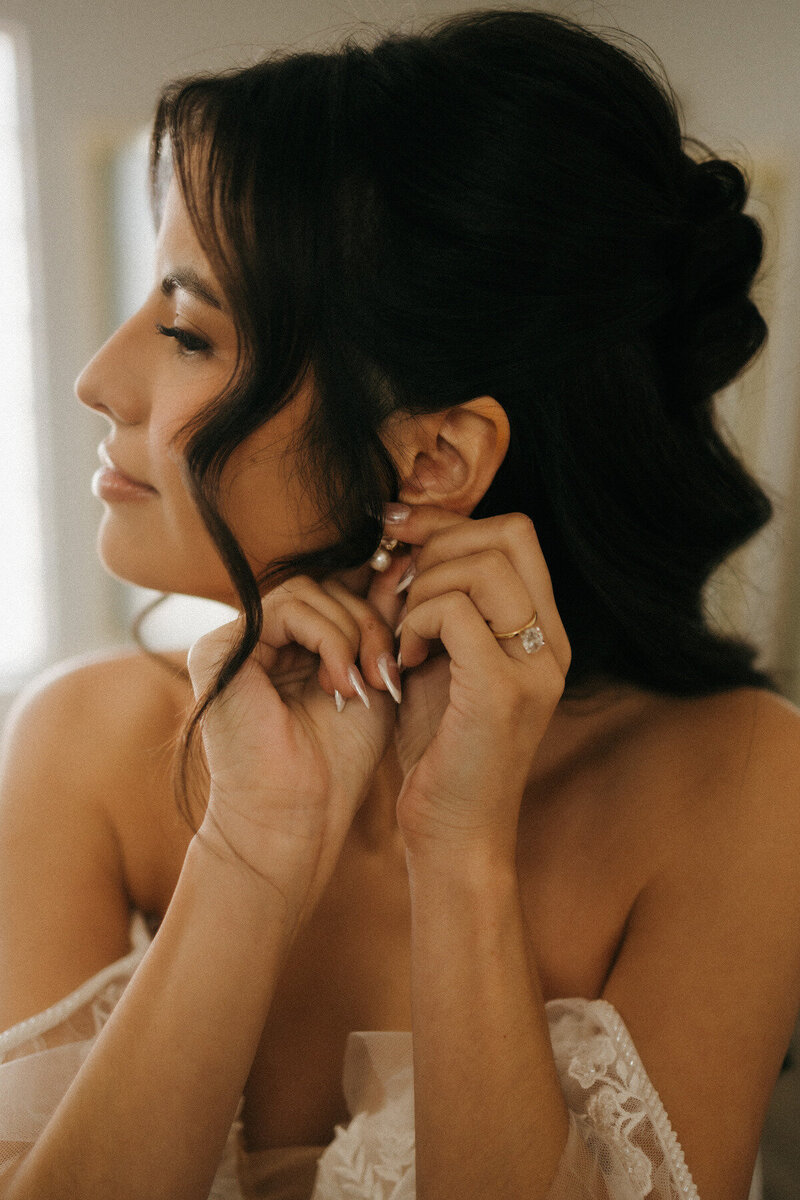 Bride getting ready on wedding day, close-up of pearl earring and engagement ring, romantic wedding detail captured by Tarah Shea Photography