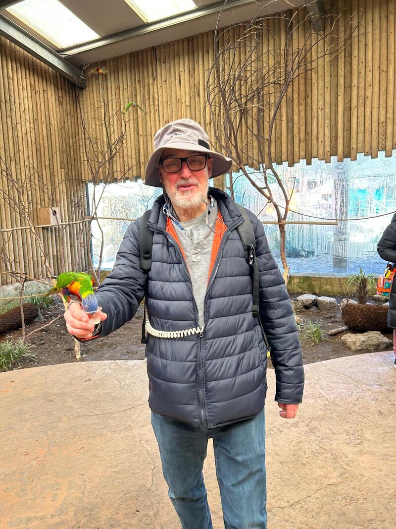 Nigel holding a parrot while using the Optune Device