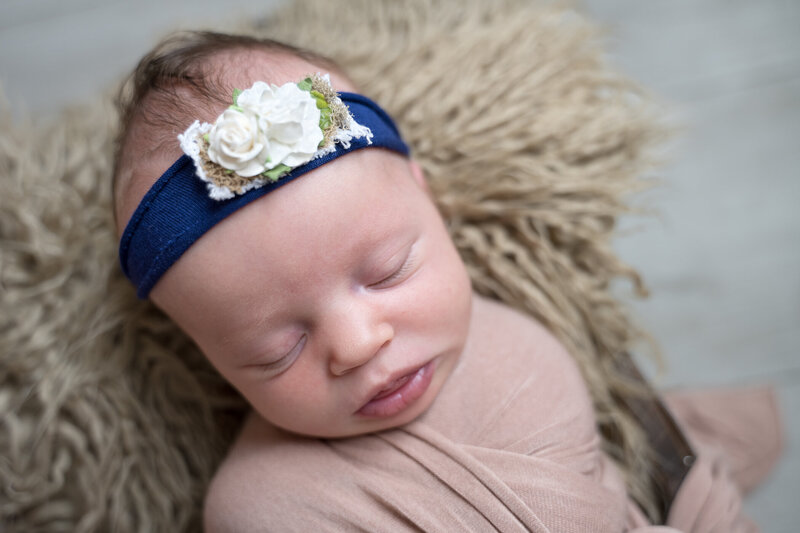 Newborn swaddled in neutrals with pale pink bonnet
