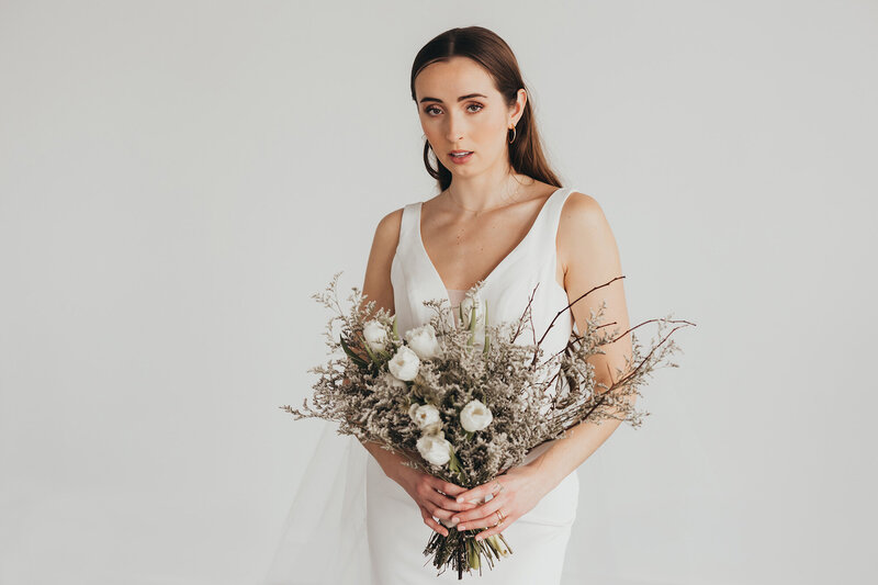 Wedding photo of bride holding bouquet in studio