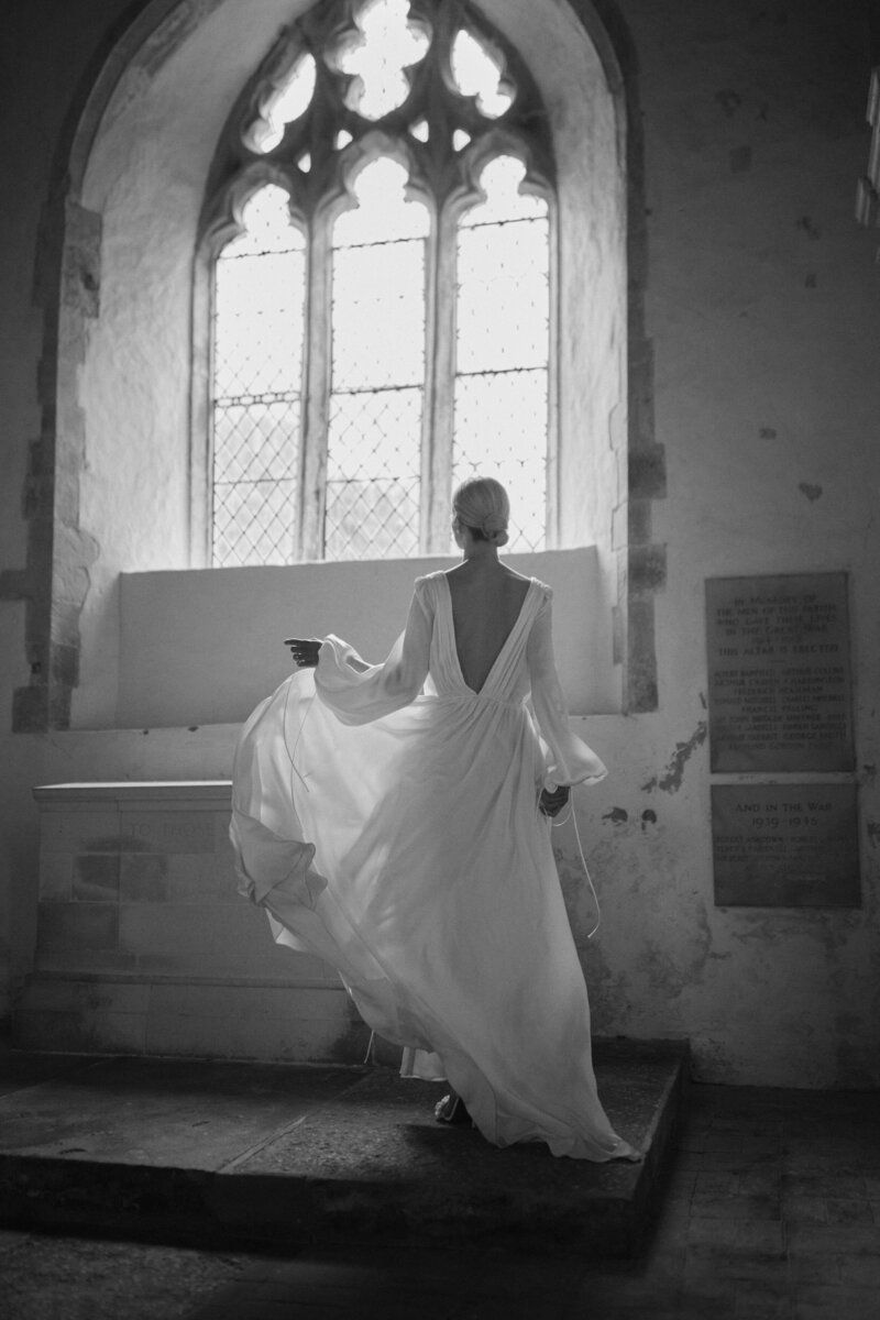 Bride wearing low v-back flowing long wedding dress in silk in church