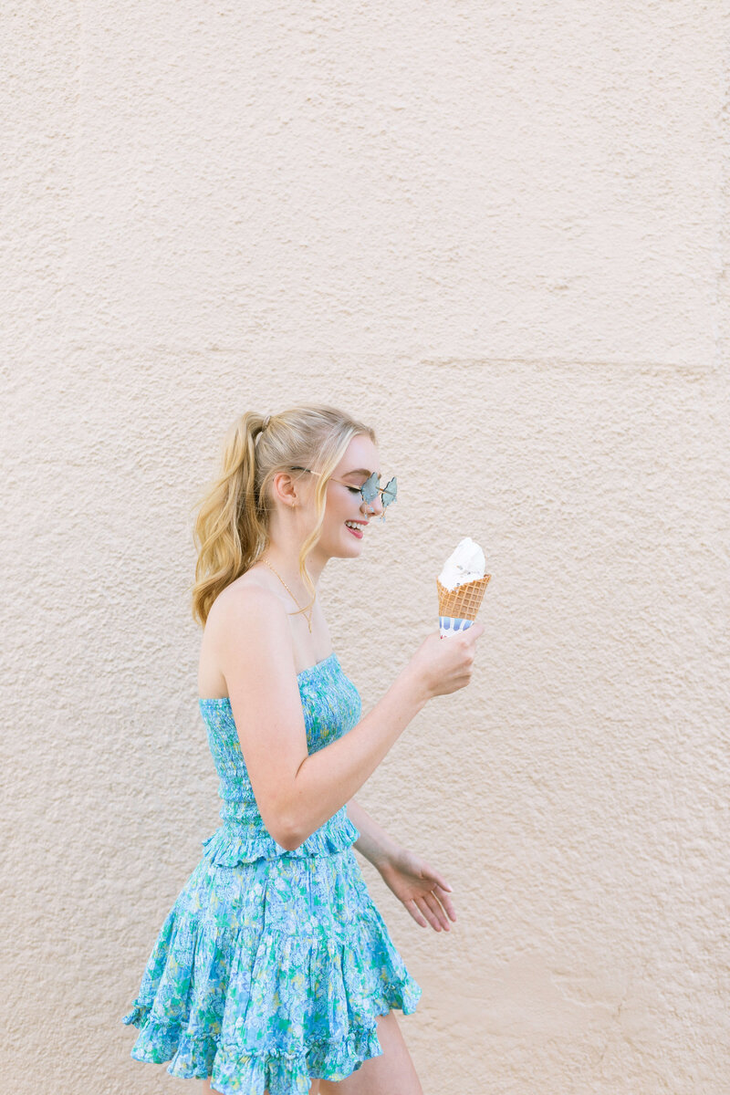 blonde girl holding ice cream cone and wearing a blue summer style dress with matching glasses