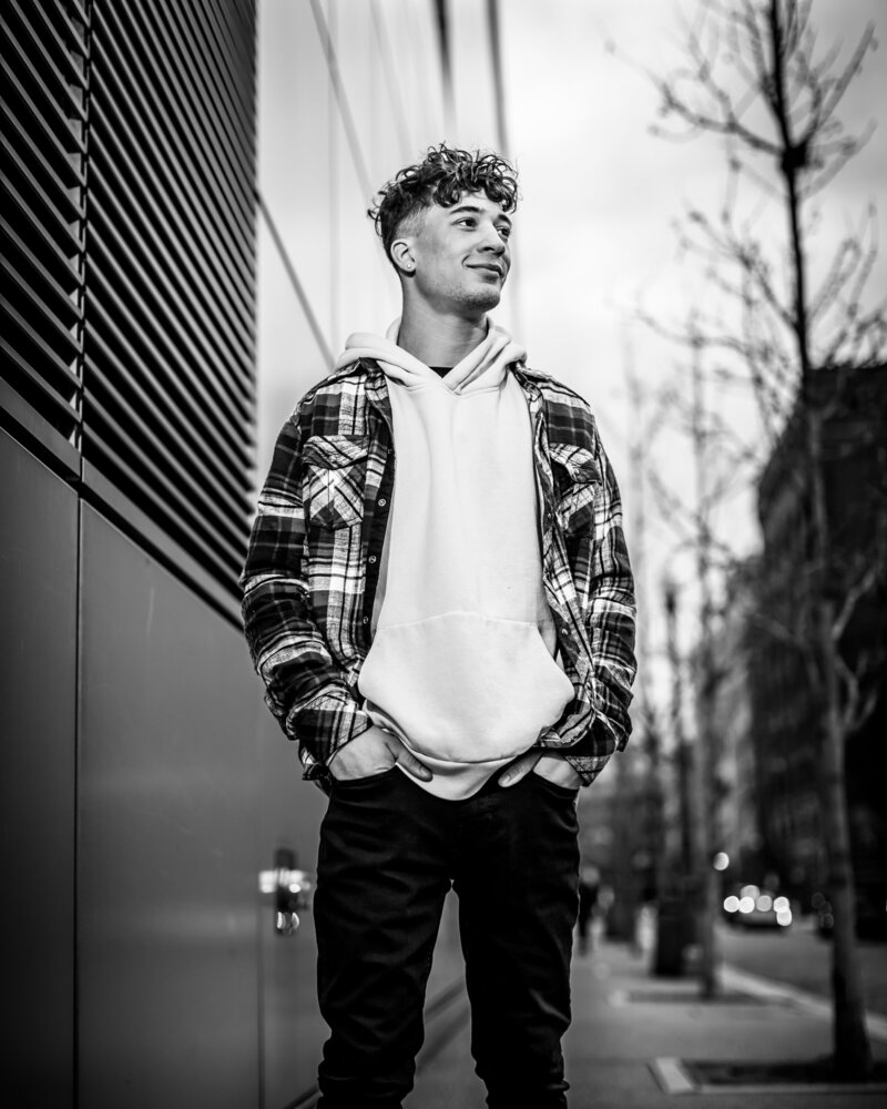 In black-and-white image of a hip teen boy having his portraits taken on the streets in Pittsburgh