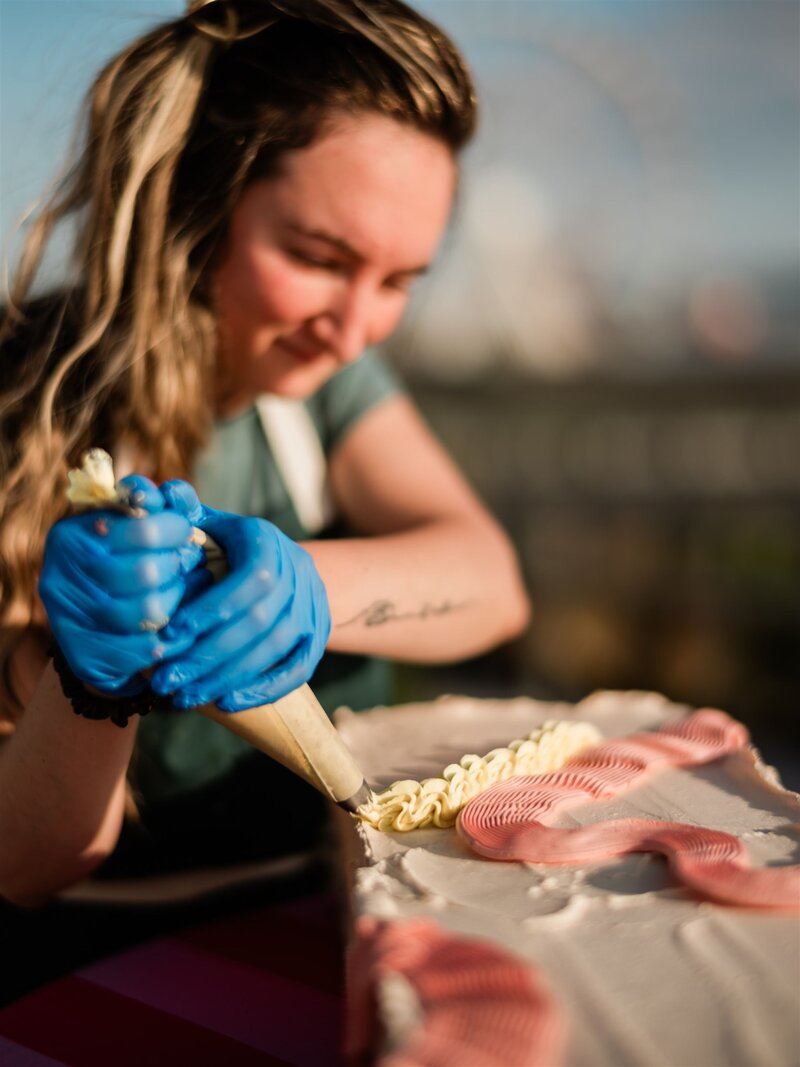 Founder of Grain Artisan Bakery decorating a gluten-free cake with buttercream frosting in the bakery’s Snohomish kitchen, representing care, craft, and community.