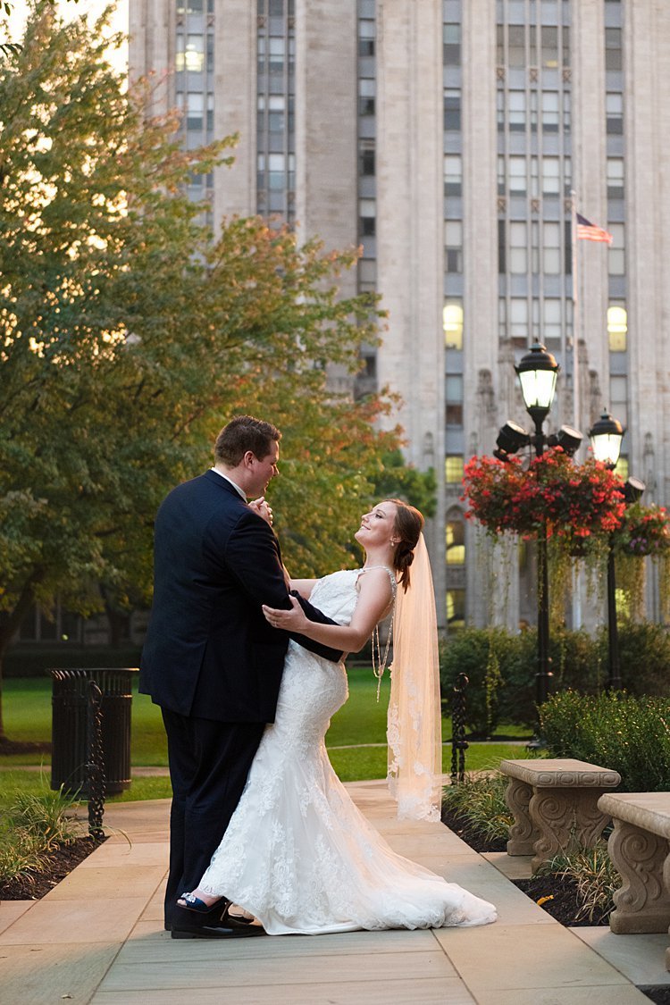 Groom dipping Bride in jewel-backed gown in front of Cathedral of Learning in Pittsburgh, PA