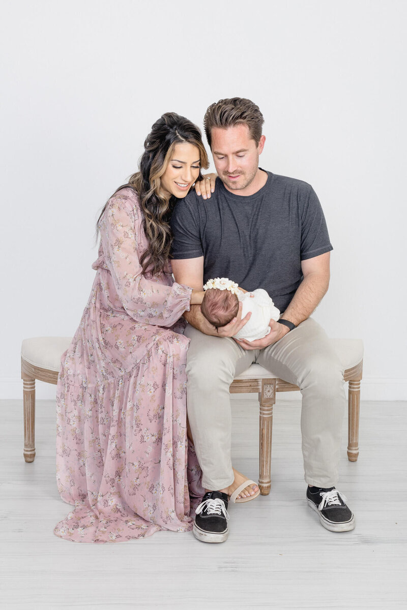 A long brown-haired pregnant woman in a long, white dress lying on the ground with her husband, both looking at each other