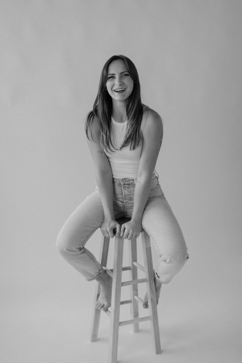 woman sitting on a wood stool laughing