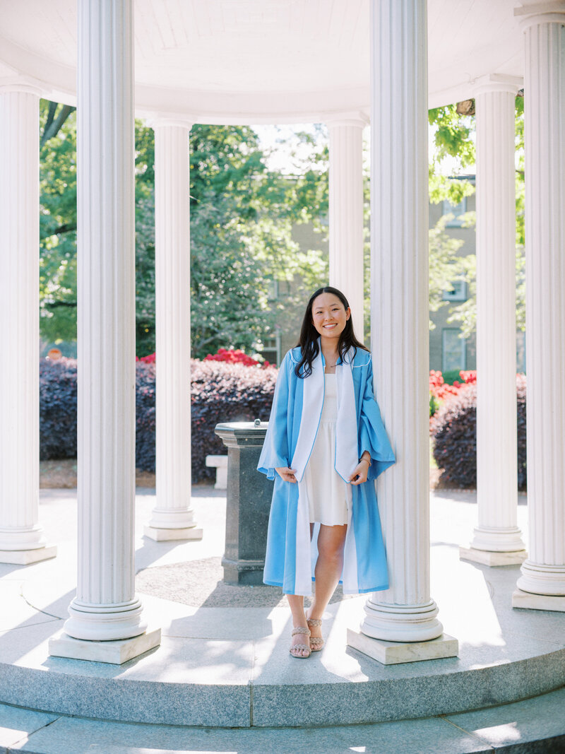 A student taking a graduation photo at UNC Chapel Hill's Old Well