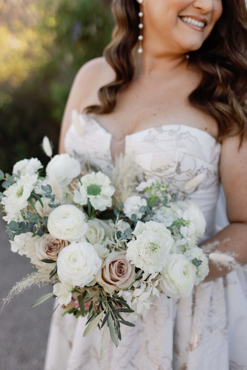 Bride looks over her shoulder while holding her white bouquet.