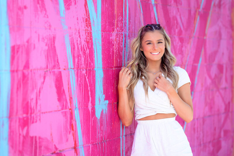 Photo of a senior high school senior against a bright pink wall