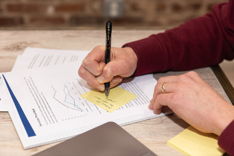 detail of a hand writing a note on a post-it over business work documents Atlanta Brand Photographer