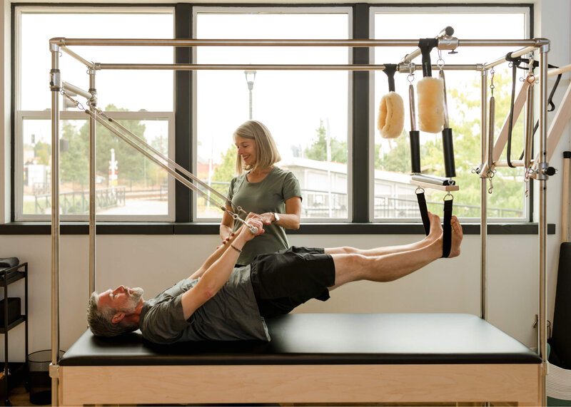 Man practicing the breathing exercise on cadillac with pilates instructor
