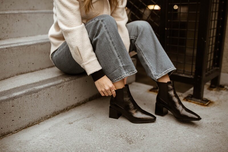woman sitting on the edge of stairs fixing her boot