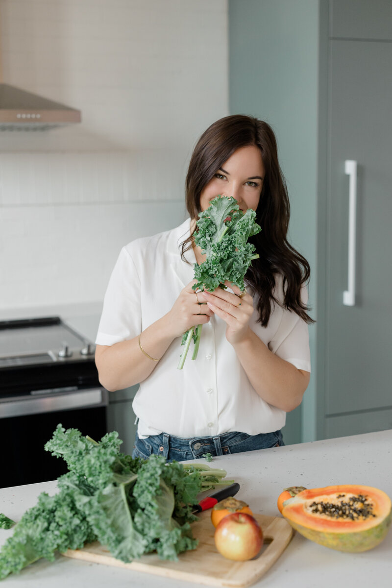 Kealy holding some leafy vegetables at the kitchen area