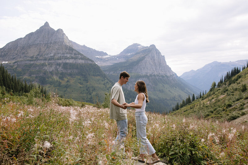couple standing in a field of flowers with glaciers in the background