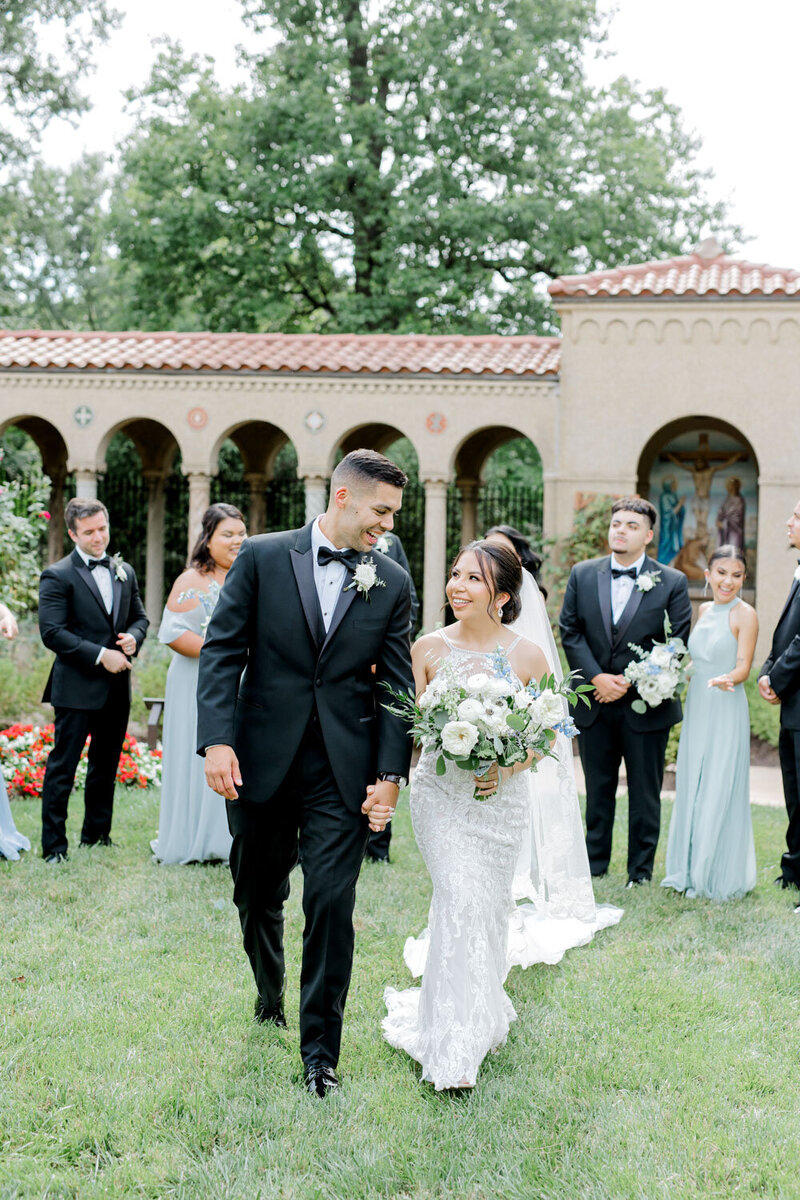 Bride and groom walking together with wedding party outdoors