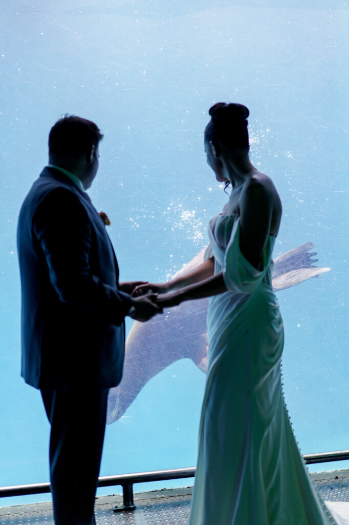 Bride and groom at ceremony on white stage under trees