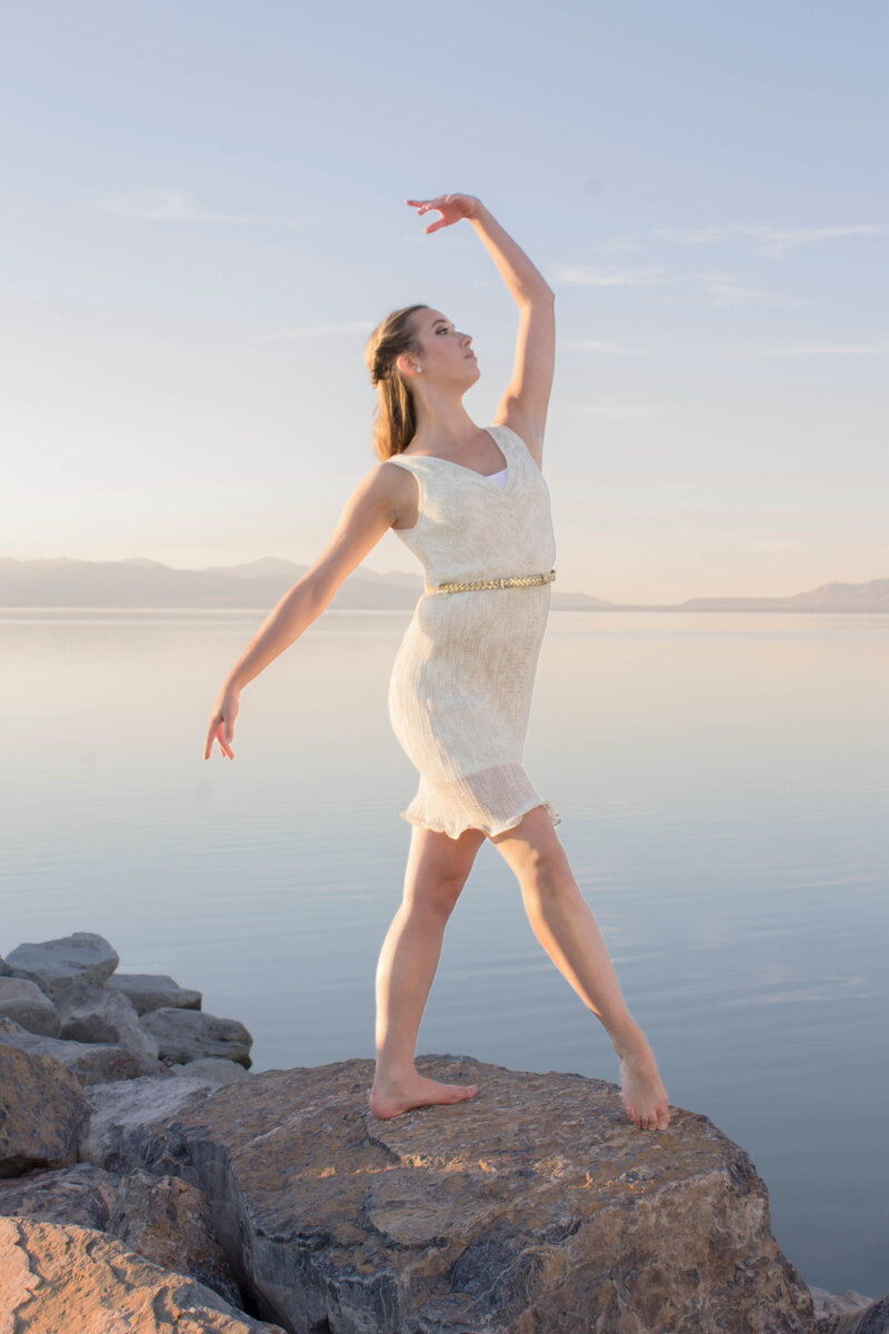 Blonde dancer poses gracefully on a rock outcropping by a beautiful lake