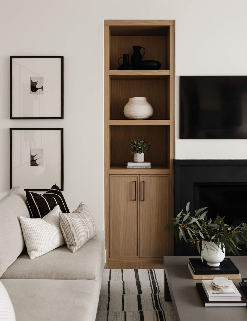 Living room with black plaster fireplace, white oak built ins and abstract artwork. 