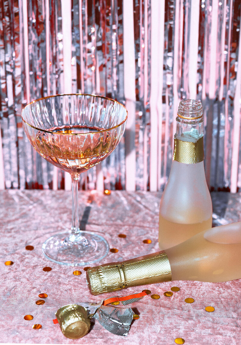 Coupe et bouteilles de champagne dans un décor scintillant couleur lilas. Décor de nouvel an imaginé par une organisatrice d'événements.