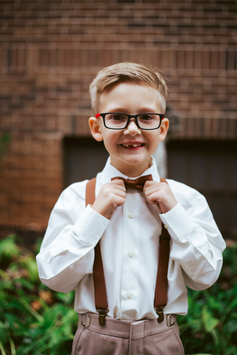 young boy in formal attire holding bow tie