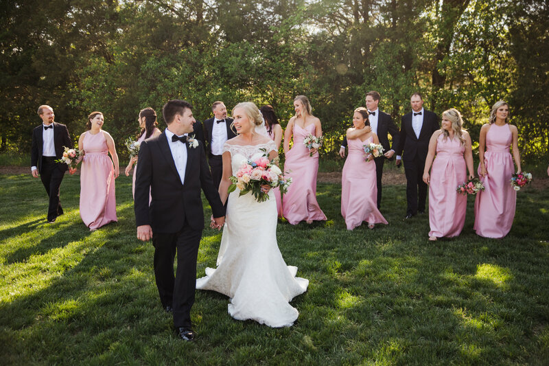 full bridal party walking and laughing with bride and groom