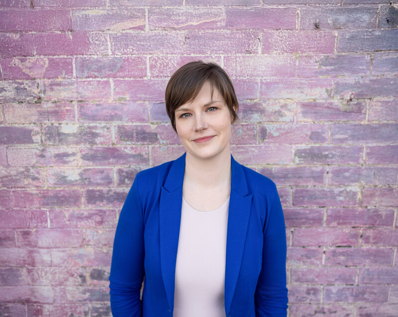 A-Baltimore-woman-poses-for-business-headshots-against-a-pink-wall-in-Maryland