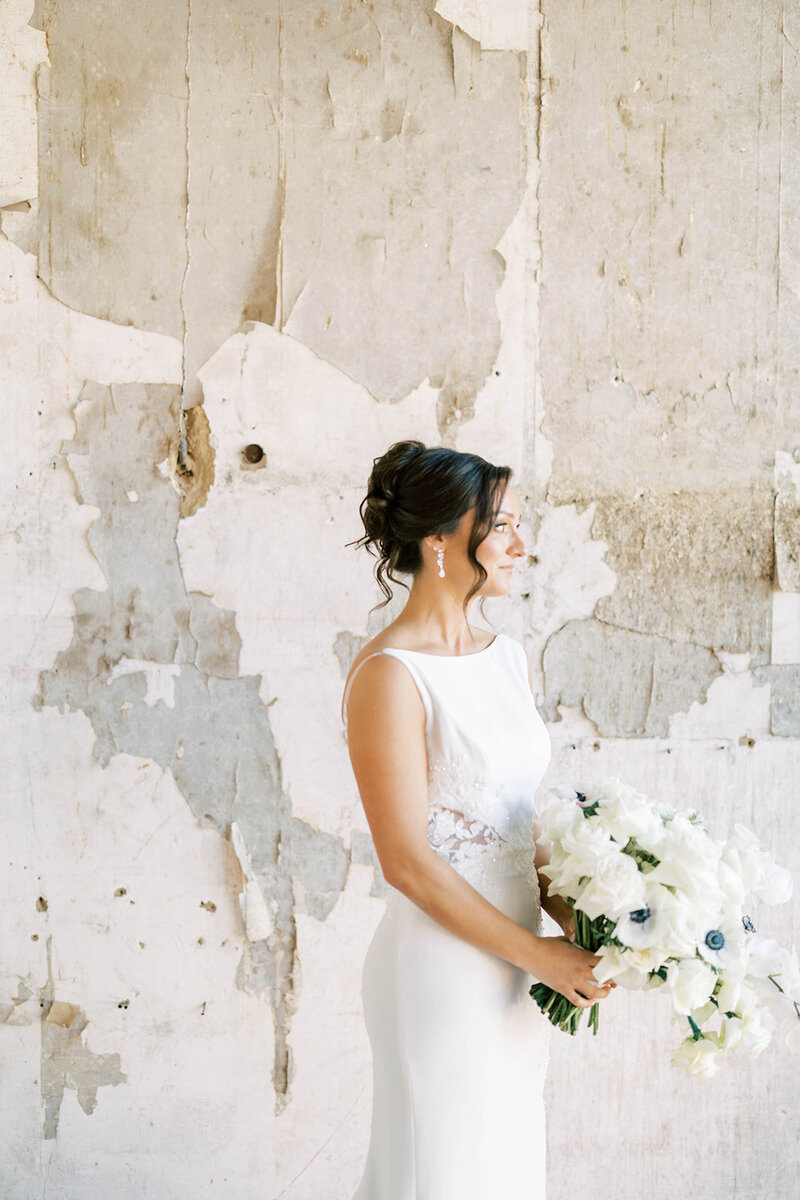 Bride holds bouquet by textured wall inside the Excelsior in Lancaster